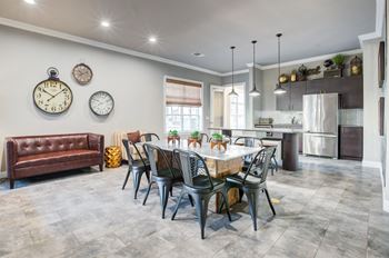 A modern dining room with a brown leather couch, a wooden table, and a kitchen in the background.